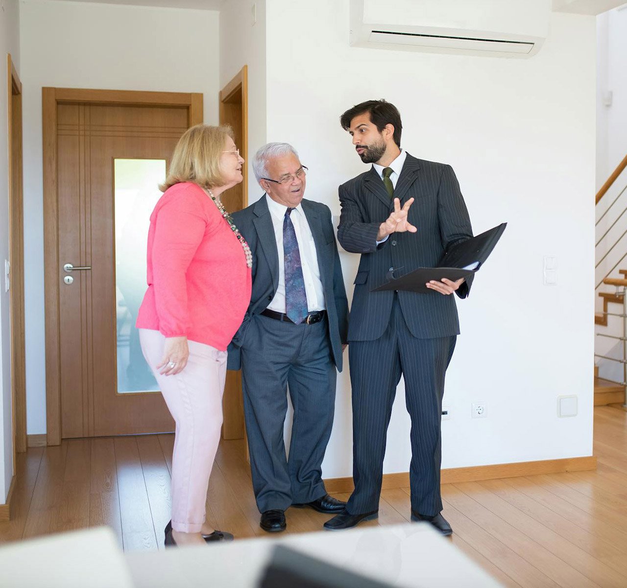 Professional property manager showing an unfurnished rental property to a prospective senior tenant couple.