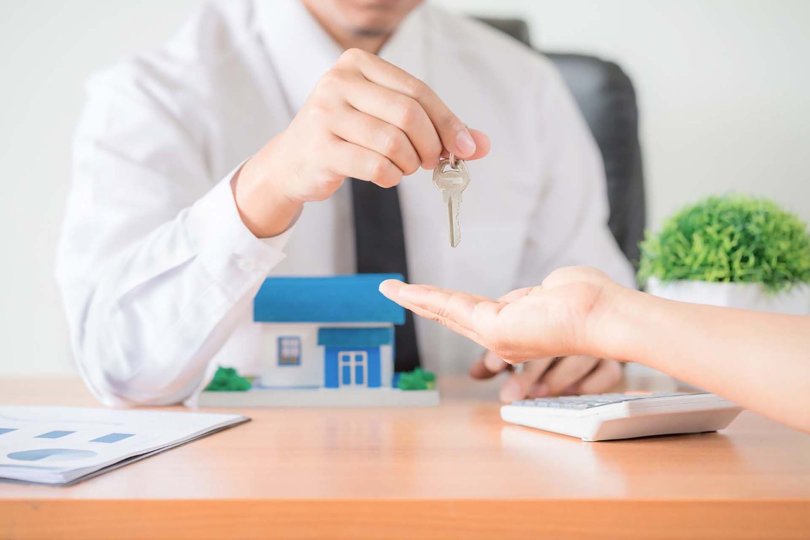 Property manager handing over house keys to a new tenant or homeowner, signifying a completed rental or sale transaction.